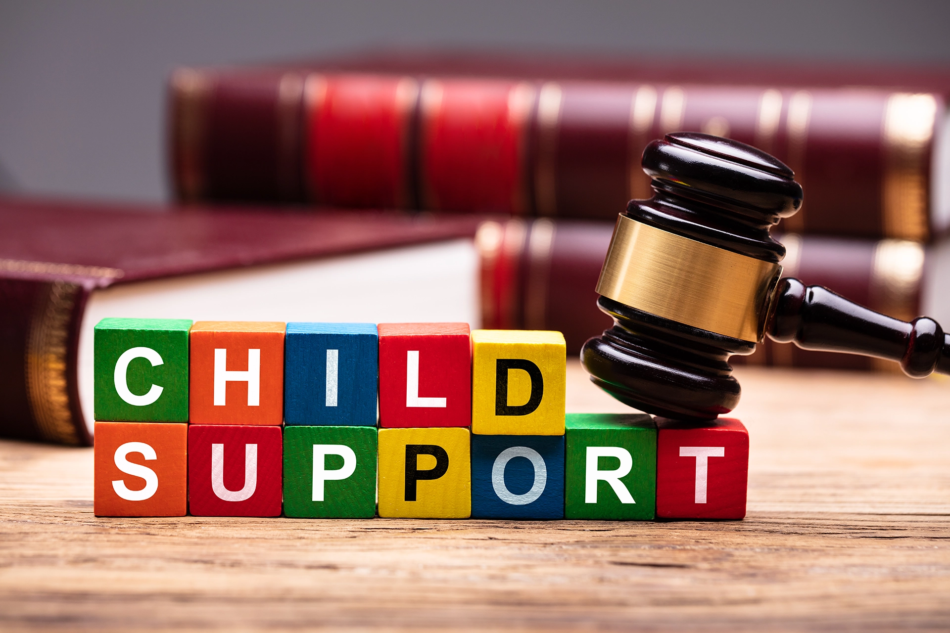 Building blocks spelling out the word “child care” with a judge’s gavel on top and books in the background.