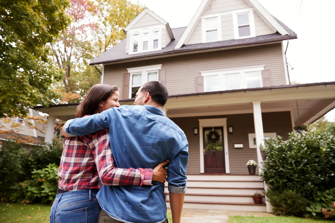 A man and a woman smile lovingly at one another as they walk toward their shared home.
