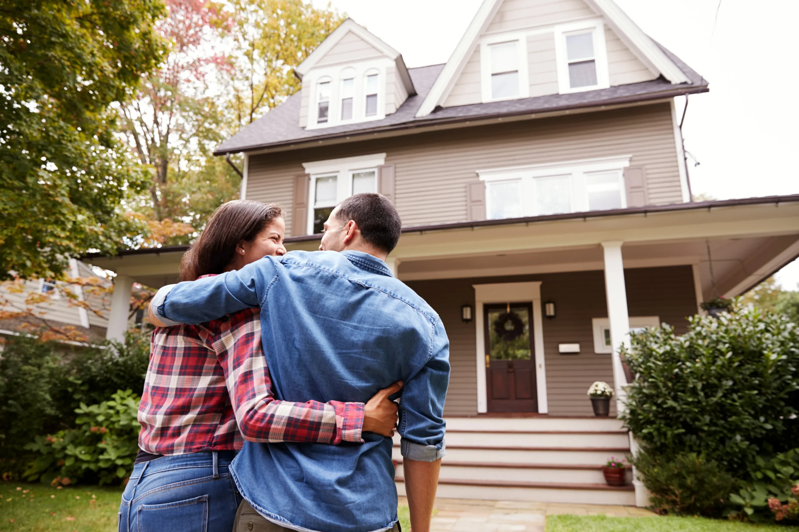 A man and a woman smile lovingly at one another as they walk toward their shared home.