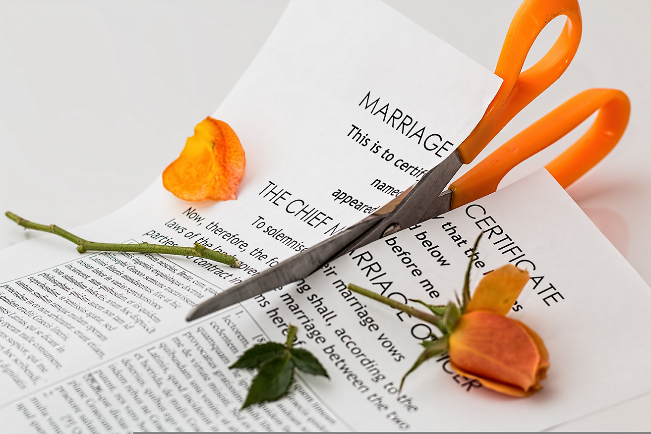 A pair of orange-handled scissors cutting through a marriage certificate, with scattered rose petals and a broken rose symbolizing divorce.