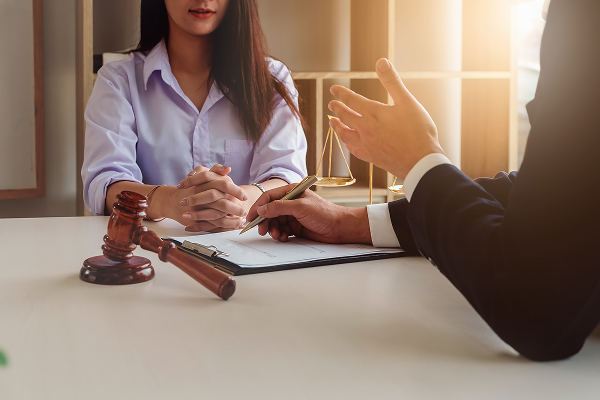 Lawyer reviewing legal document with client, gavel and scales of justice on desk