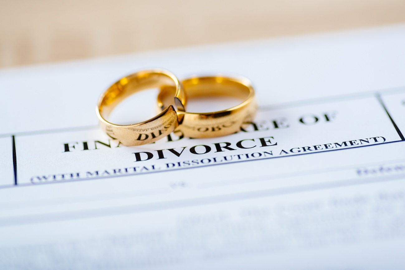 Divorce papers with a pair of gold wedding rings placed on top.